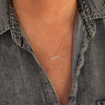 A close-up of a décolletage wearing a Pavé NANA Necklace in yellow gold and a cable chain, with a grey denim shirt. 