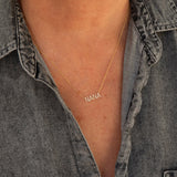 A close-up of a décolletage wearing a Pavé NANA Necklace in yellow gold and a cable chain, with a grey denim shirt. 