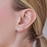 Close-up of two Pavé Charm Studs -  Star of David in white gold and Hamsa in yellow gold in a blonde woman's ear. 