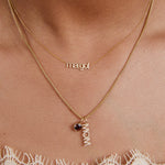 Gold necklace with 'margot' and 'mom' pendant on a person's neck