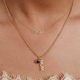 Gold necklace with 'margot' and 'mom' pendant on a person's neck