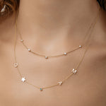 Quintet Diamond Necklace layered with Gold initial necklace on a person's neck.