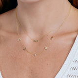 Gold necklace with 'olivia' pendant on a person wearing a white top.