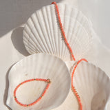 An Endless Summer Bracelet and Necklace in Mykonos laid on three big white shells against a white fabric background. 