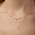 Gold 'MAMA' necklace layered with quintet diamond necklace on a person's neck