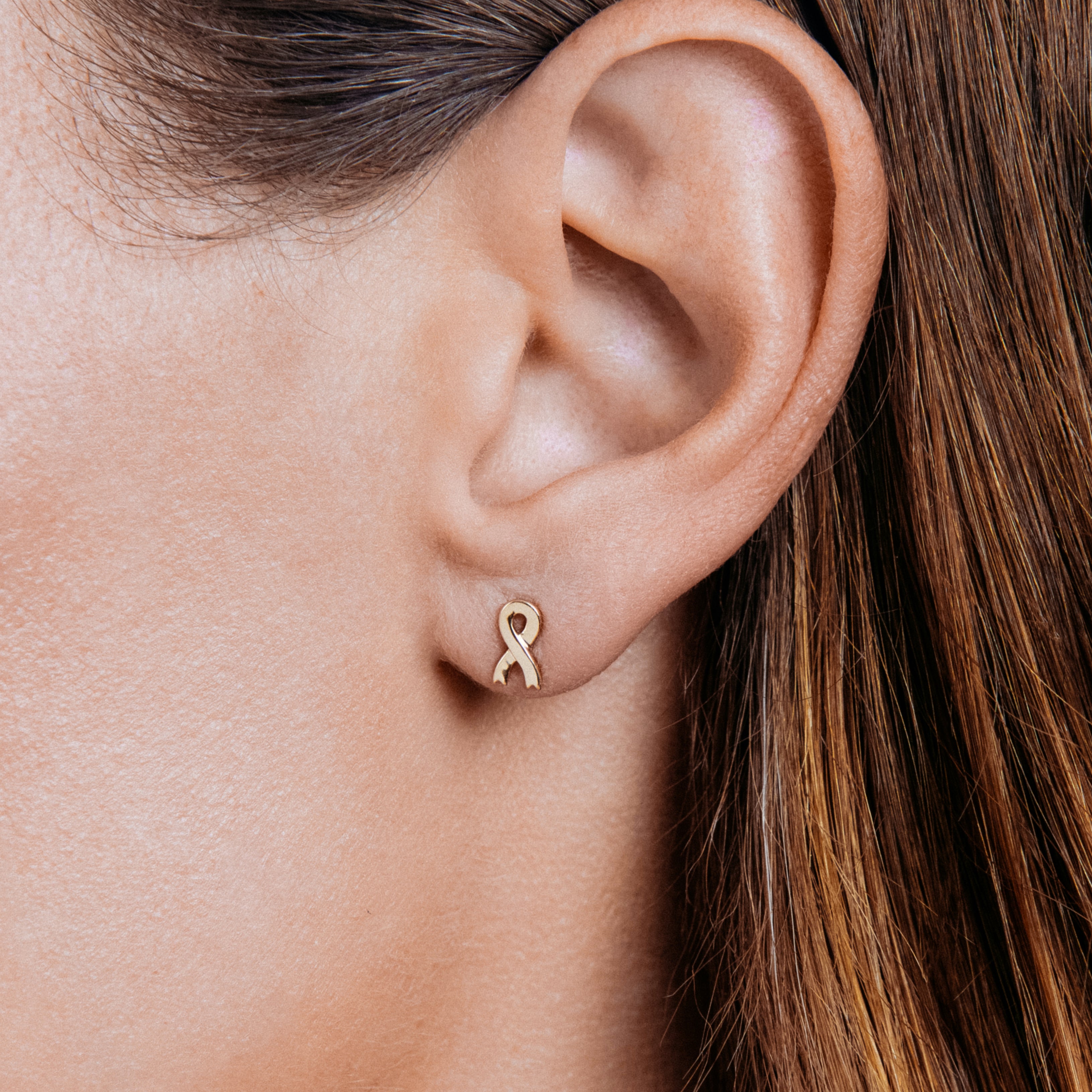 Ribbon stud earring worn on an ear.