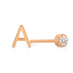 A rose gold monogram earring set, featuring a mini letter A stud and a mini diamond stud on a white background. 