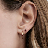 Close-up of a Birthstone Stud and Birthstone Hoop - Ruby (July) in a woman's ear,  with her brown hair visible. 