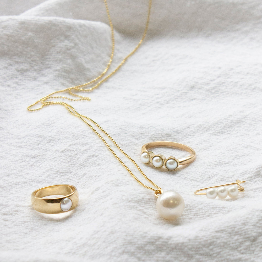 Gold and pearl jewelry on a white fabric background