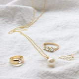 Gold and pearl jewelry on a white fabric background