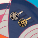 Two Skylight Hoops, one in silver and one in gold, on a colourful geometric-patterned surface. 