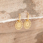 Gold Skylight Hoops on a textured beige surface.