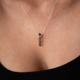 Close-up of a décolletage wearing The Courage Retreat Necklace with a black top. 