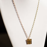 A Virtues Pendant - Square in yellow gold on a white necklace stand. 