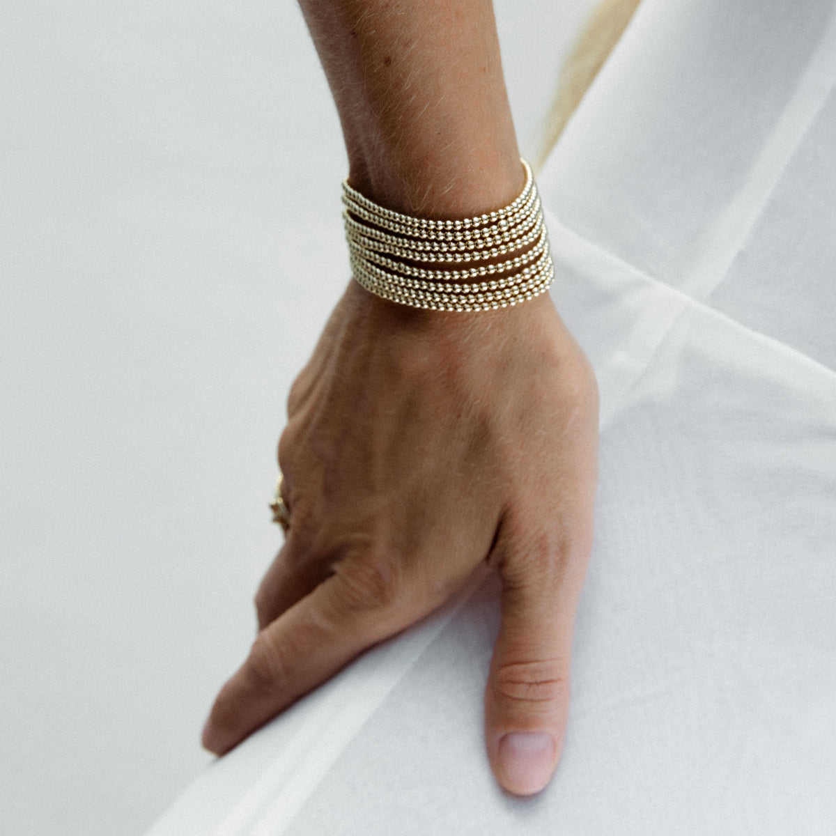 A hand wearing multiple stacked Little Bubble Bracelets against a white background.
