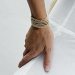 A hand wearing multiple stacked Little Bubble Bracelets against a white background.