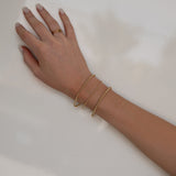 A hand wearing a Classic Bubble Bracelet Set, two Delicate Beaded Bands and a Twinkle Twinkle ring against a neutral background.