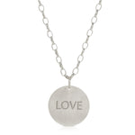 The back of a Virtues Pendant - Circle in sterling silver with 'LOVE' engraved on a white background. 