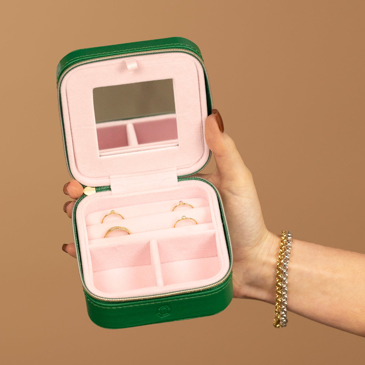 A Travel Jewelry Case - Green/Pink on a light brown background. 