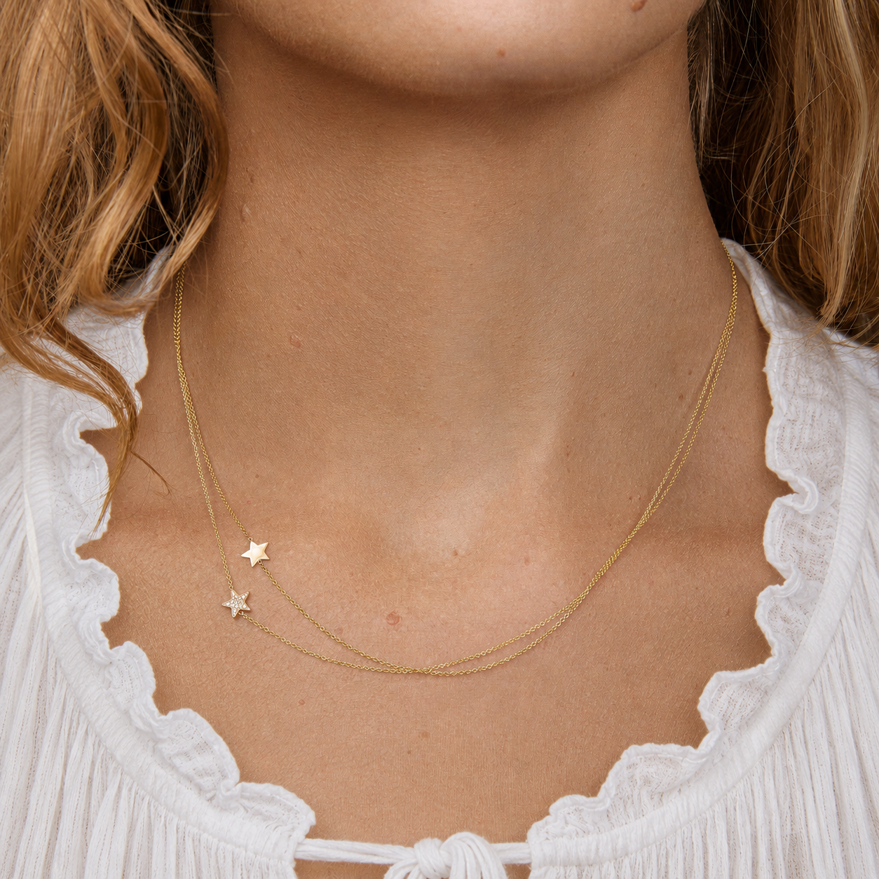 Close-up of a person wearing a gold necklace with star pendants.