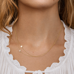 Close-up of a person wearing a gold necklace with star pendants.