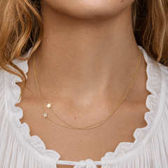 Close-up of a person wearing a gold necklace with star pendants.