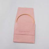 A gold vermeil Flirt Bangle inside a pink Maya Brenner jewelry pouch. 