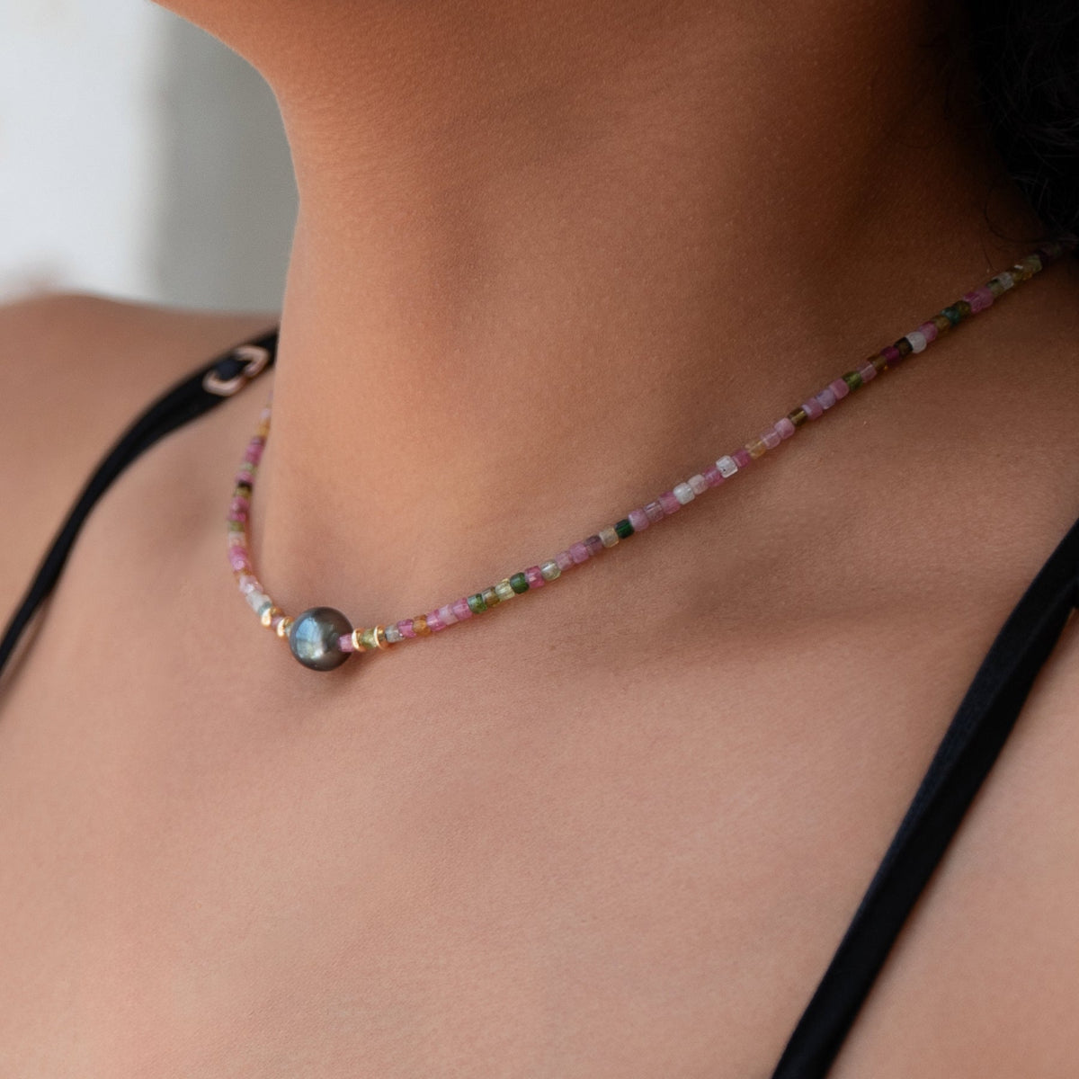 A close-up of a neck wearing an Endless Summer Bracelet - Sweet Escape, styled with a black strap top. 