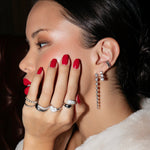 A Braided Ring, The Evermore Ring, Cosmo Martini Ring, Love on the Rocks Ring, Make It a Double Ring, the Night Cap Ear Cuff, Triple Sec Diamond Earring and a Diamond Cascade Earring, all in white gold, worn by a woman with a cream fluffy coat, red nails and red lipstick. 
