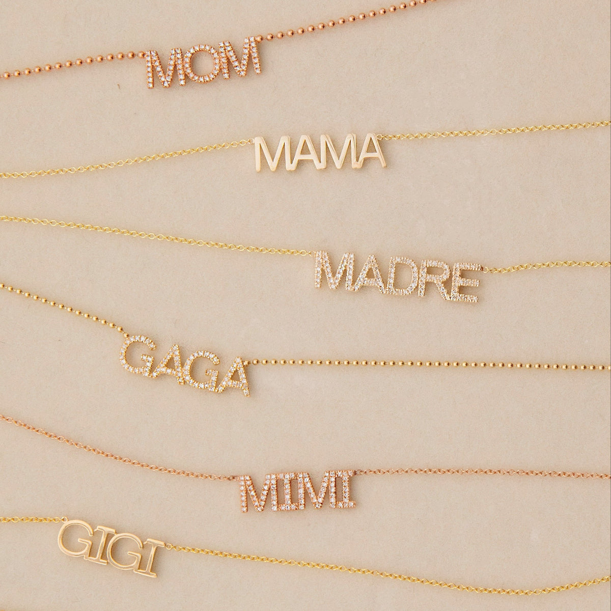 Pavé MOM, MADRE, GAGA and GIGI and MAMA and GIGI Necklaces in either yellow or rose gold on a light beige background. 