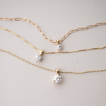A Duchess Diamond Pendant on an Element Long Link Chain, a Princess Diamond Pendant on The Slide Chain and a Queen Diamond Pendant on a bead Chain in yellow gold against a light grey background. 