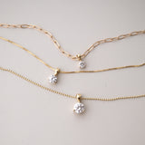 A Duchess Diamond Pendant on an Element Long Link Chain, a Princess Diamond Pendant on The Slide Chain and a Queen Diamond Pendant on a bead Chain in yellow gold against a light grey background. 