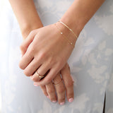 A close-up of a woman’s hands wearing an Off the Cuff Bracelet, a Starstruck Diamond Bracelet, an Open Diamond Ring and a Pavé Diamond Ring, against a white and light grey floral background.