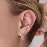 Close-up of a woman's ear wearing a Link Hoop, Birthstone Hoop and Double Ear Cuff. 