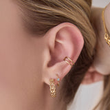 Close-up of a woman's ear wearing a Link Hoop, Birthstone Hoop and Double Ear Cuff. 