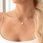 Close-up of a woman's décolletage wearing a C'est Moi Deco Necklace in yellow gold, with a white singlet top.