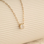 A C'est Moi Deco Necklace in yellow gold against a cream stripe background. 