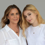 Maya Brenner and her daughter each wearing an Enamel Gold Unity Pendant (one small and the other large) with a white top against a light grey background. 