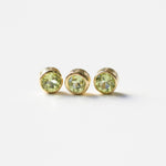 Three yellow gold peridot birthstone charms on a white background. 