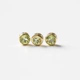 Three yellow gold peridot birthstone charms on a white background. 