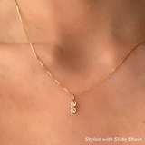 A close-up of a neck wearing a yellow gold Petite Nameplate Pendant with 'ava' on a necklace. 