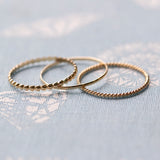 Delicate Trio Stacking Rings on a light blue textured background. 