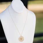 A Skylight Necklace in yellow gold on a white mannequin against a blurred background. 