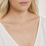 A close-up of a woman's neck wearing a gold necklace with a letter C charm. 