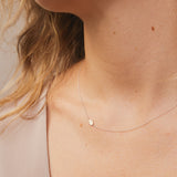 A close-up of a neck wearing a white gold 14k Gold Asymmetrical Charm Necklace - Hamsa with a cable chain. 