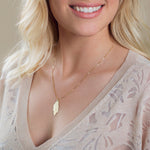 Close-up of a blonde woman wearing a 20th Anniversary Leaf Necklace, with a light beige knit and background.