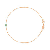 Rose gold bracelet with a small emerald green birthstone charm on a white background.
