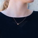 A close-up of a neck wearing a 14k Gold Asymmetrical Charm Necklace - Heart, styled with a navy knit. 