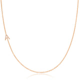 A rose gold necklace with a pave letter A charm on a white background. 