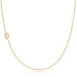 A rose gold necklace with a pave letter B charm on a white background. 